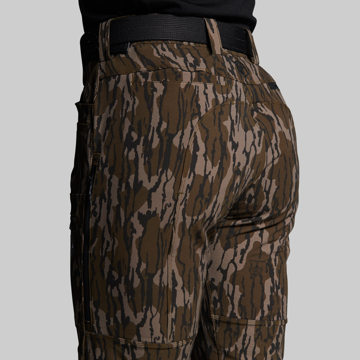 Close-up rear view of a person wearing camouflage cargo pants with a black belt, shown against a plain light gray background.