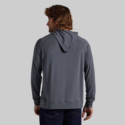 A man viewed from the back wearing a dark gray hooded sweatshirt and dark blue jeans, set against a solid light gray background.
