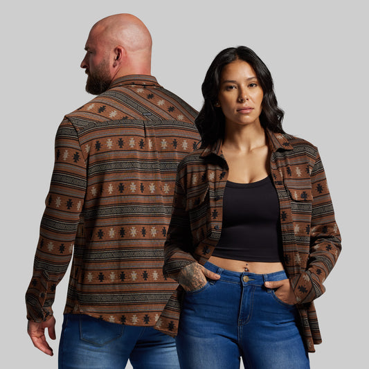 Man and woman wearing patterned shirts and jeans on a plain background