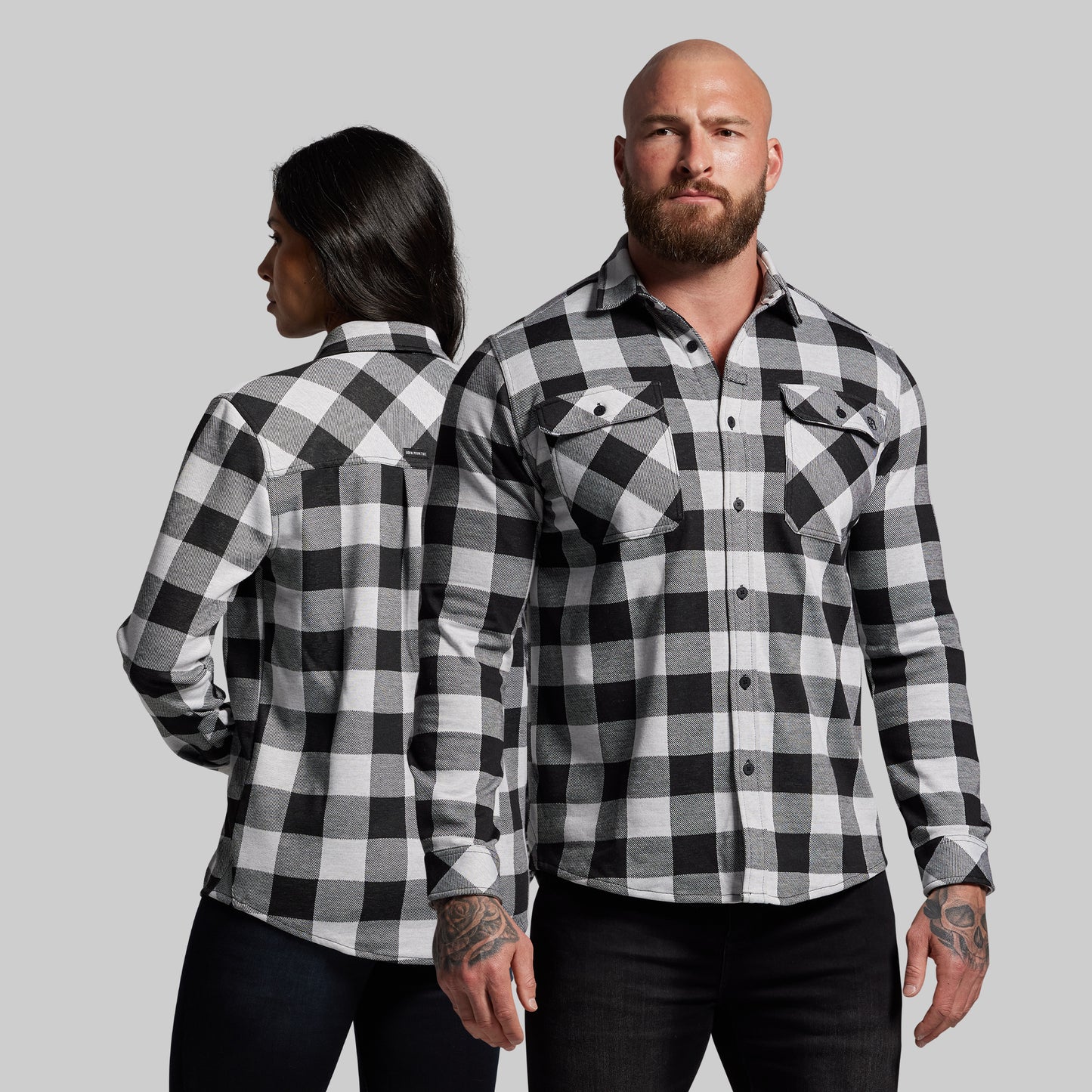 Two people wearing black and white checkered shirts against a gray background