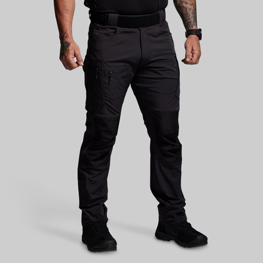Person wearing black tactical pants on a gray background