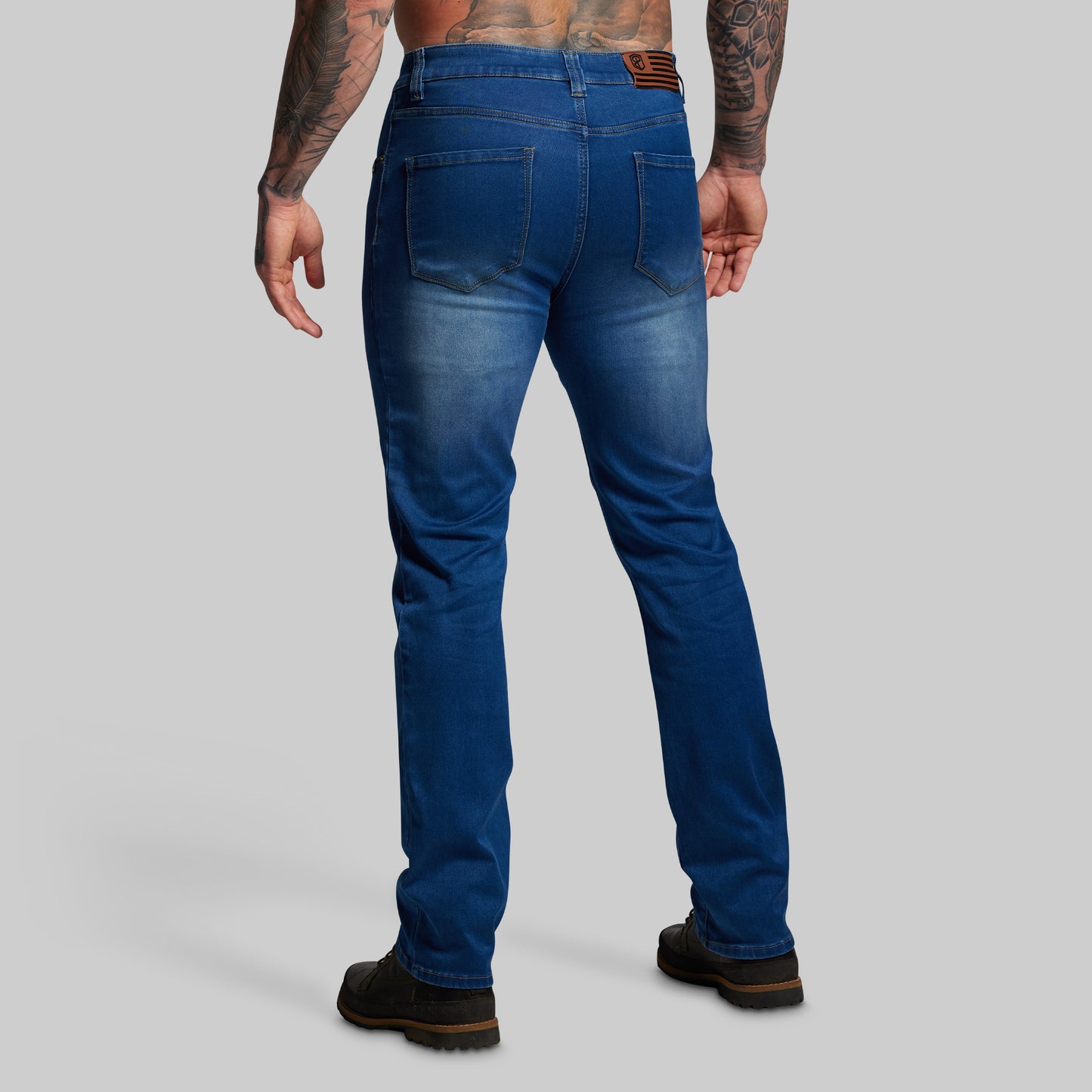 Person wearing blue jeans on a gray background