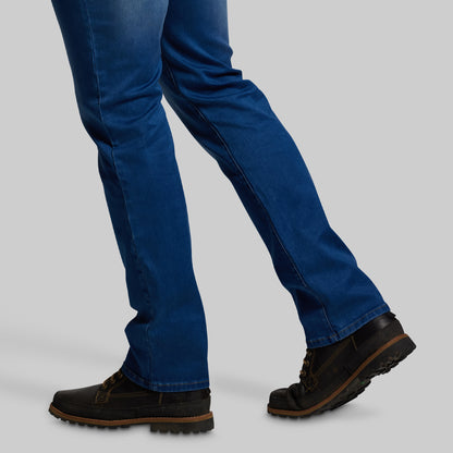 Blue bootcut jeans and black shoes on a gray background