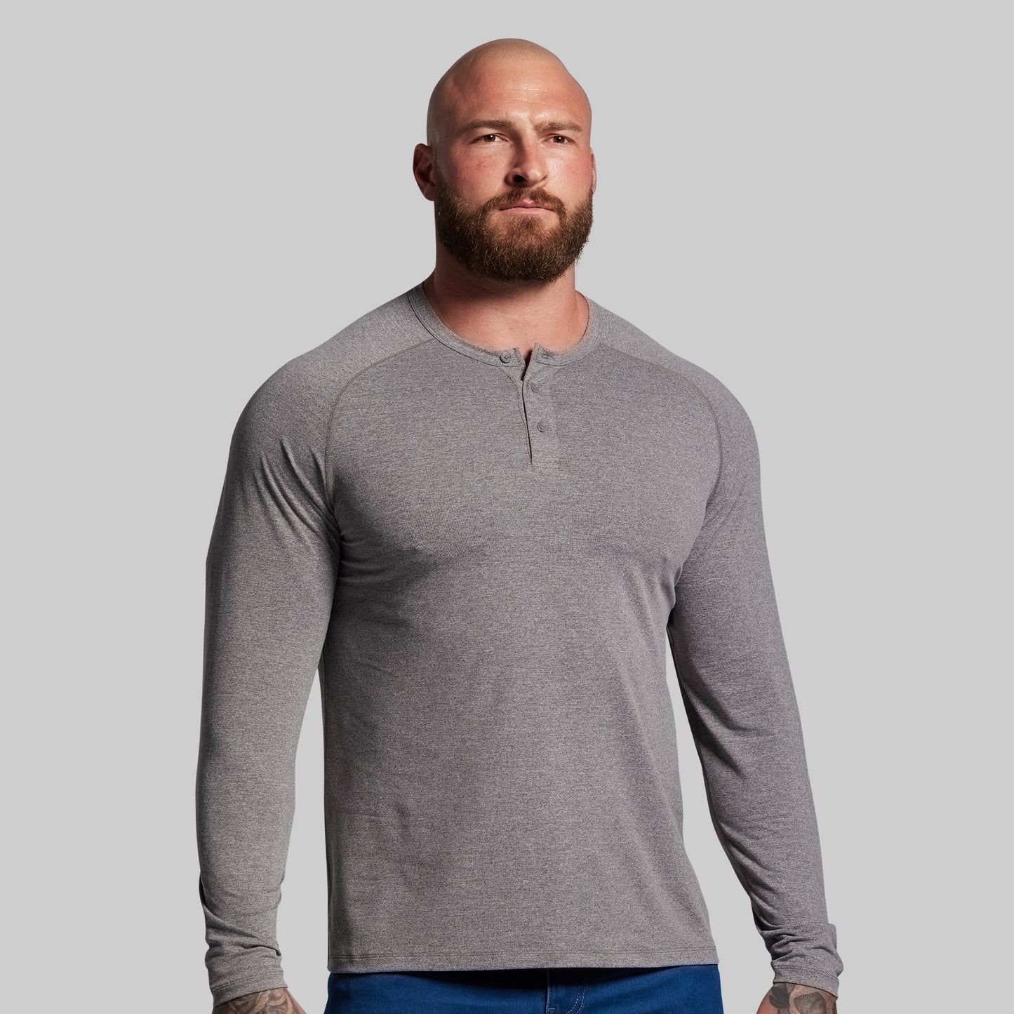 Man wearing a gray long-sleeve henley shirt against a plain background