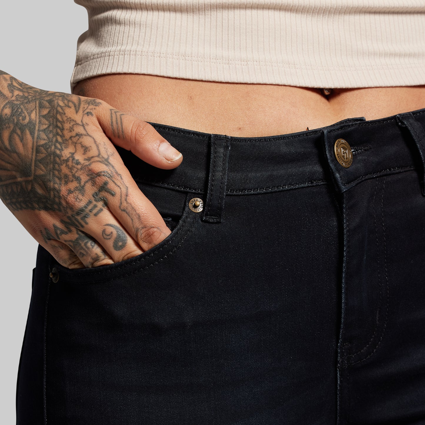 Person wearing black pants with a tattooed hand on a light gray background