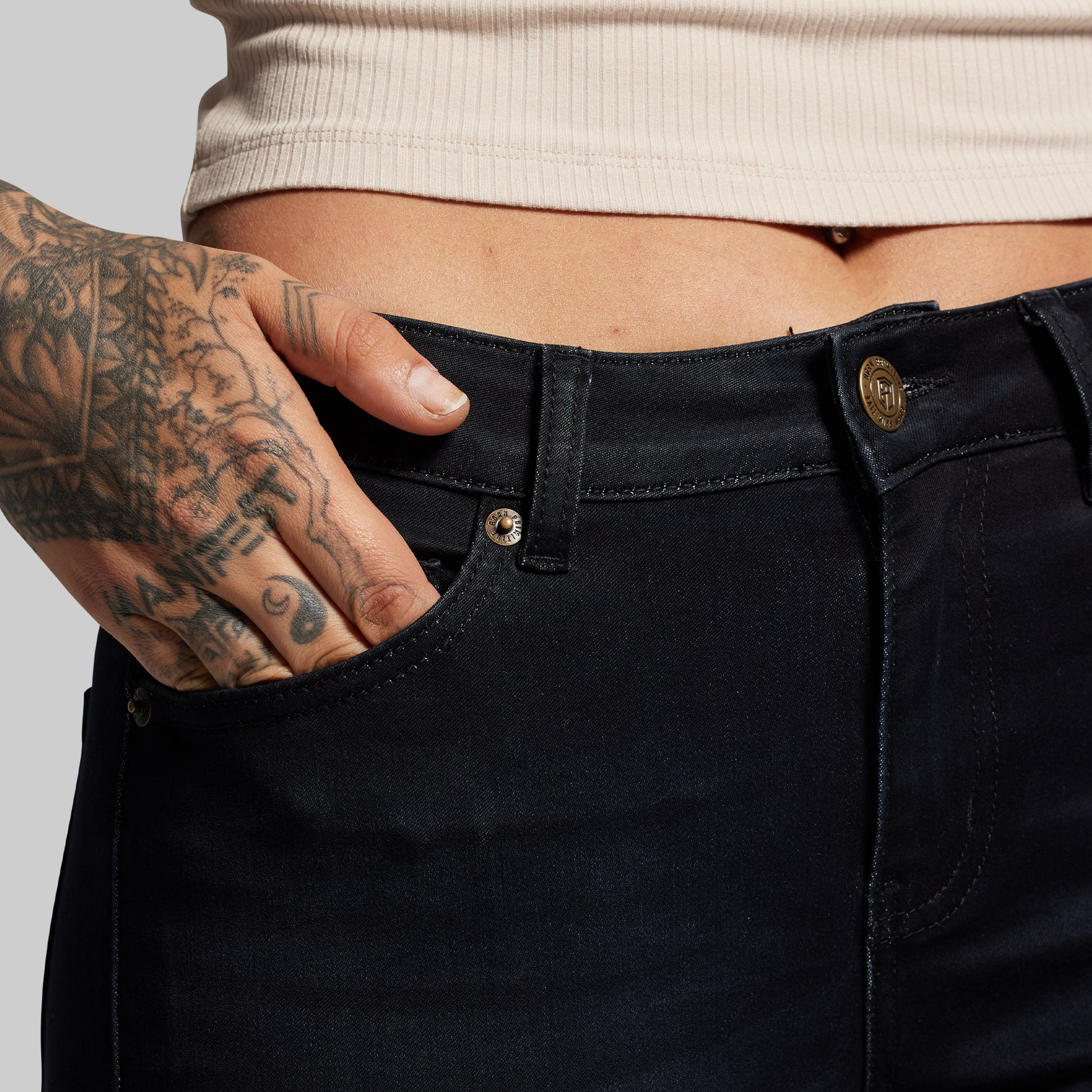 Person wearing black pants with a tattooed hand on a light gray background