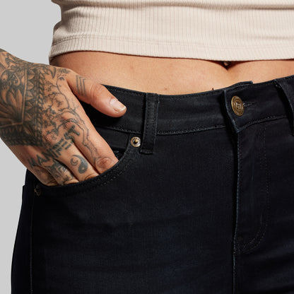 Person wearing black pants with a tattooed hand on a light gray background