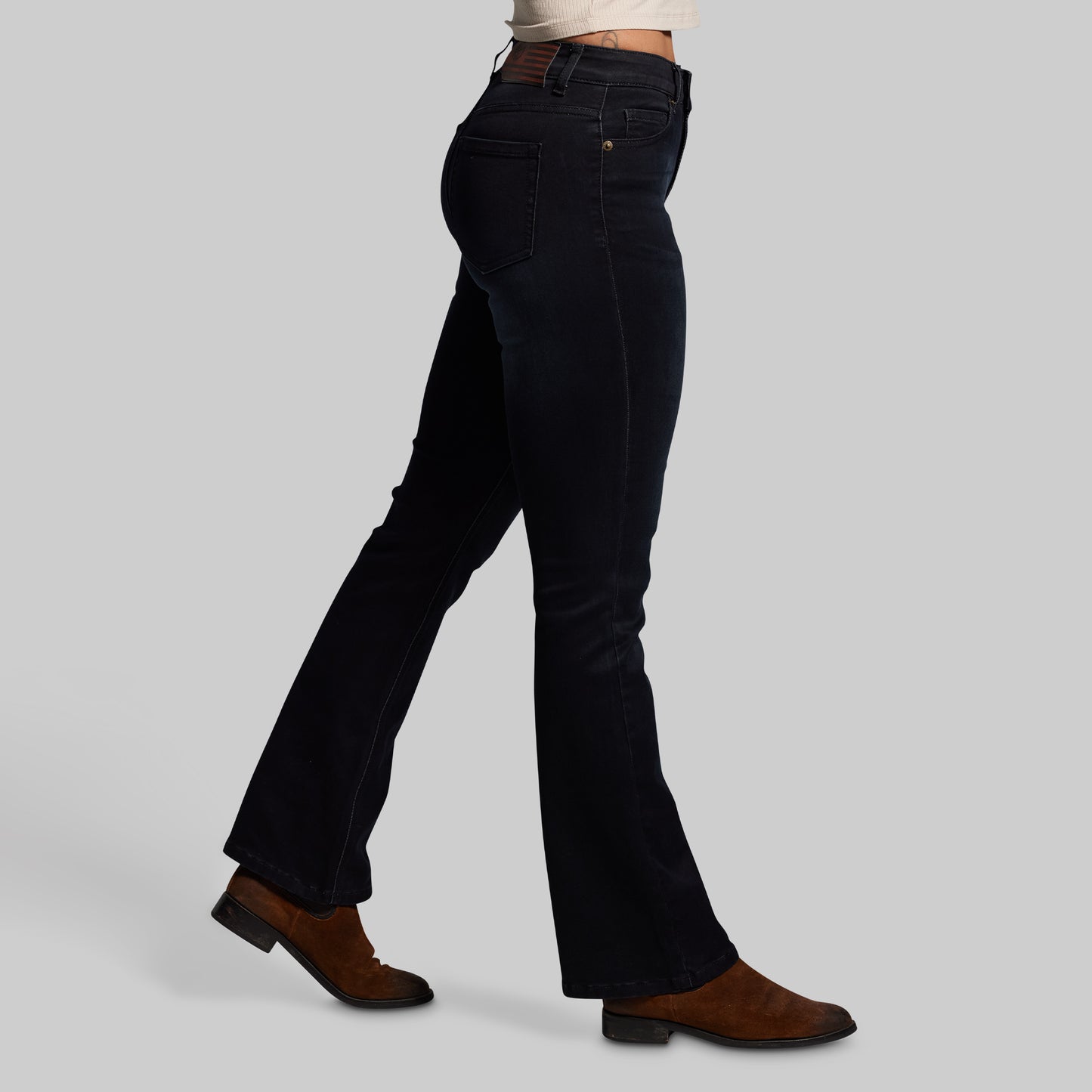Person wearing black flared jeans on a gray background