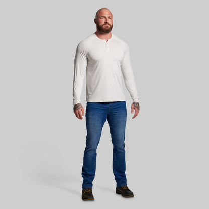 Man wearing a white long-sleeve shirt and blue jeans on a gray background