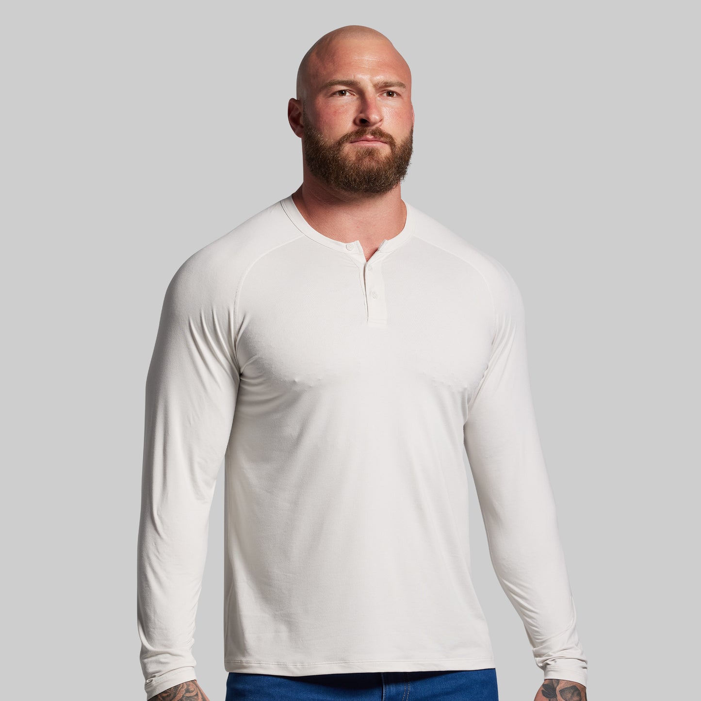Man wearing a white long-sleeve shirt against a gray background