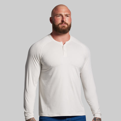 Man wearing a white long-sleeve shirt against a gray background