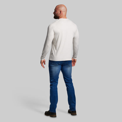 Man wearing a white long-sleeve shirt and blue jeans on a gray background