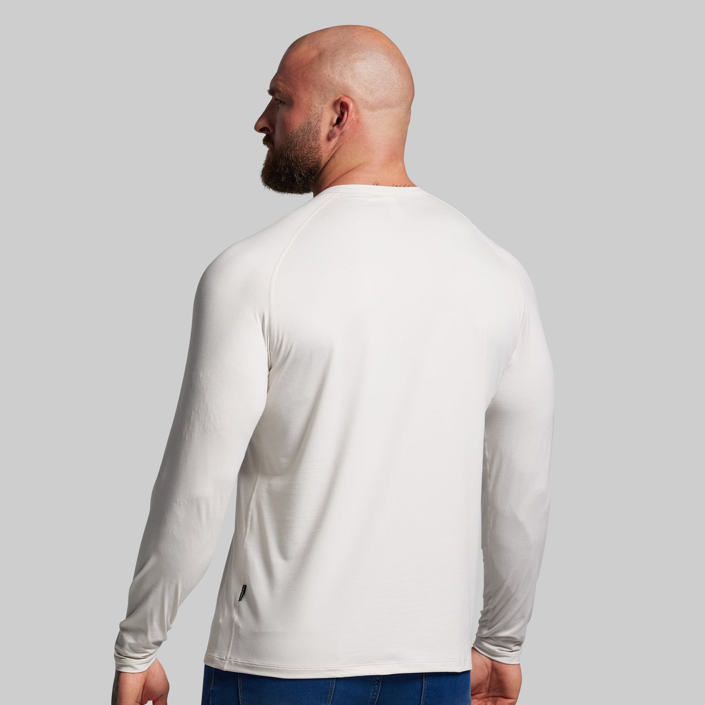 Man wearing a white long-sleeve shirt against a gray background