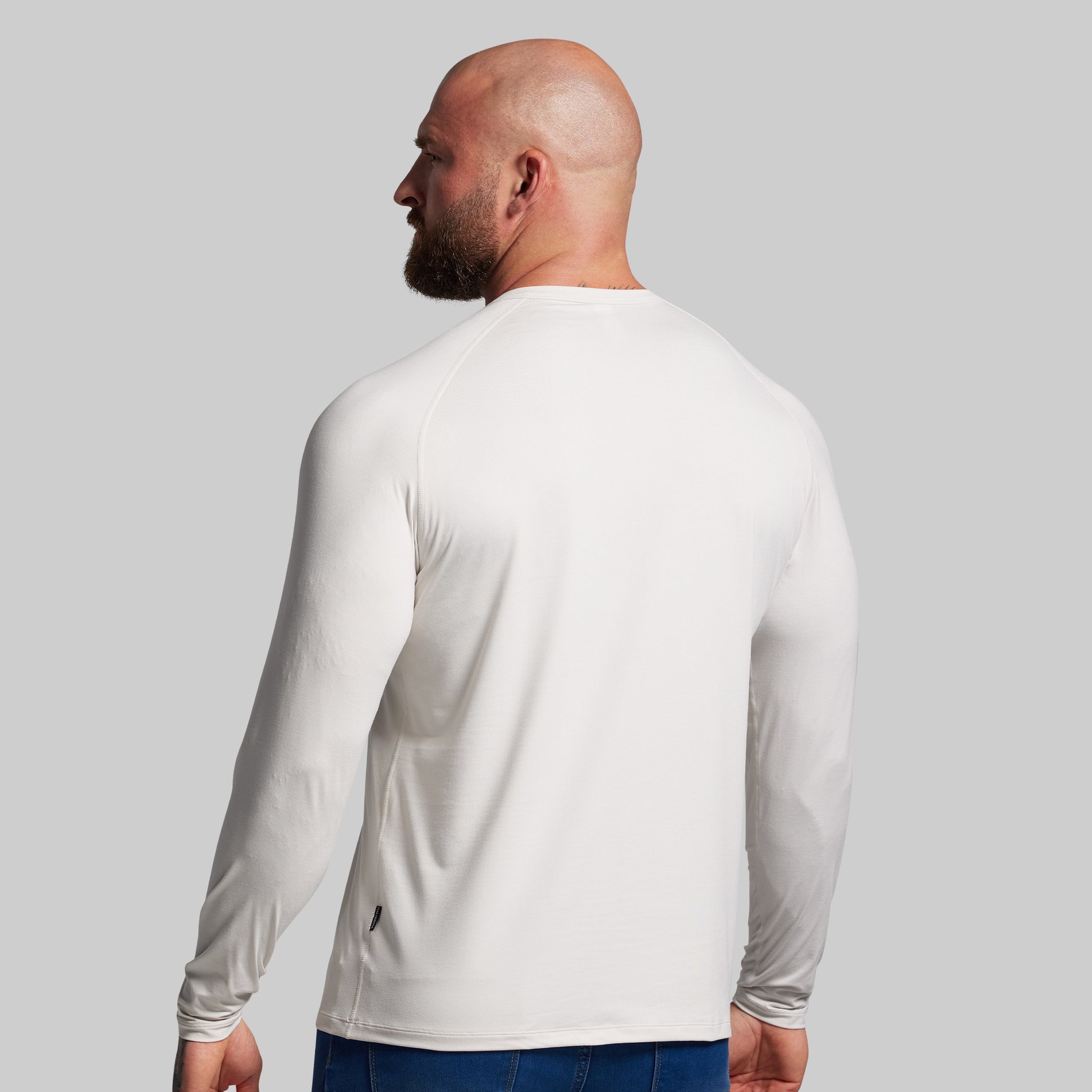 Man wearing a white long-sleeve shirt against a gray background