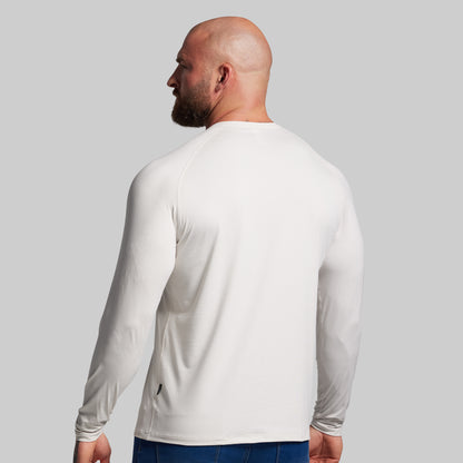 Man wearing a white long-sleeve shirt against a gray background