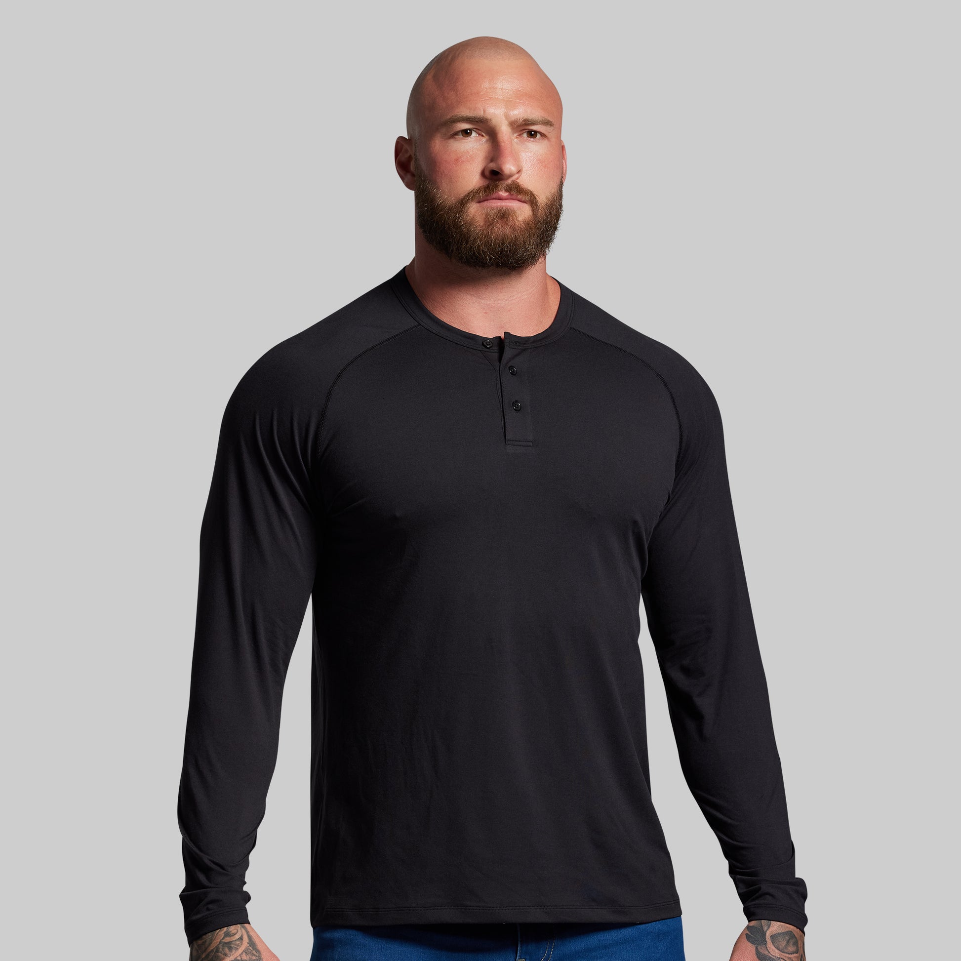 Man wearing a black long-sleeve shirt against a gray background