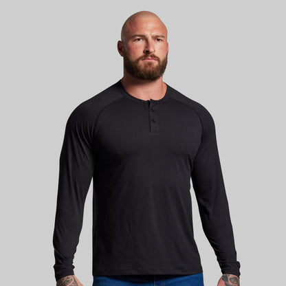 Man wearing a black long-sleeve shirt against a gray background