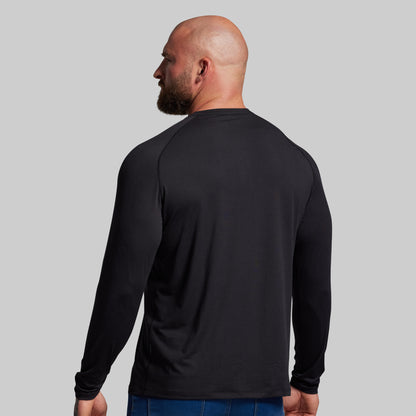 Man wearing a black long-sleeve shirt on a gray background