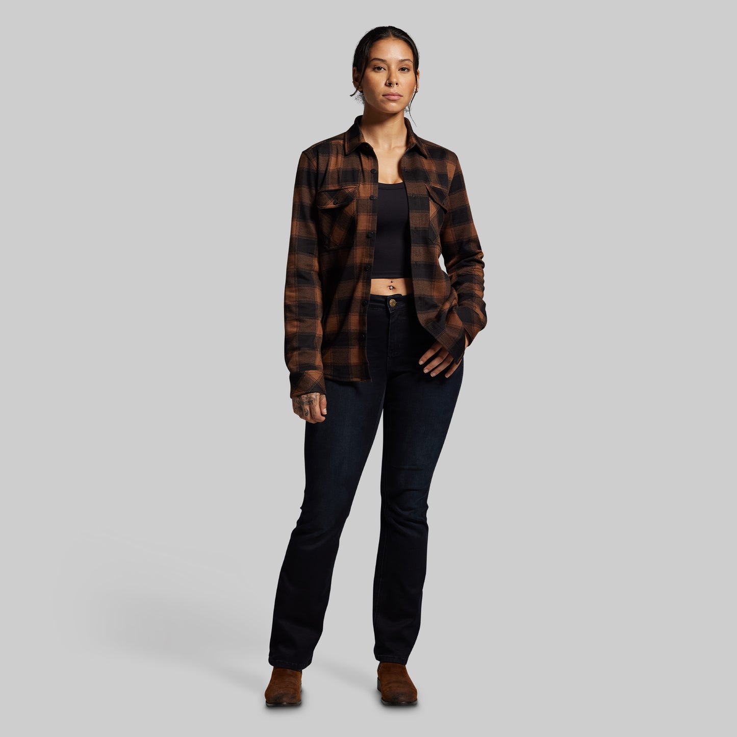 Person wearing a plaid shirt and black pants on a gray background