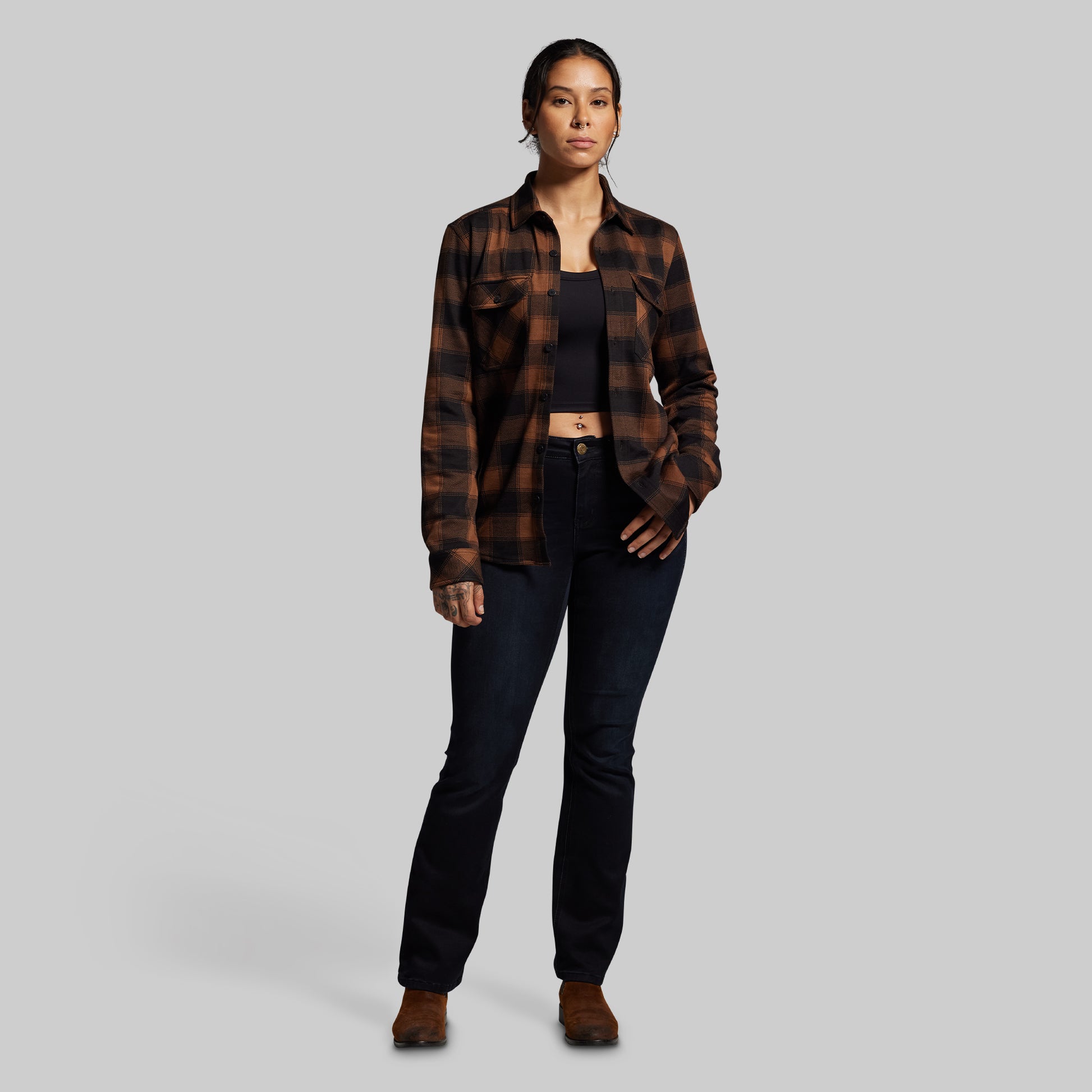 Person wearing a plaid shirt and black pants on a gray background