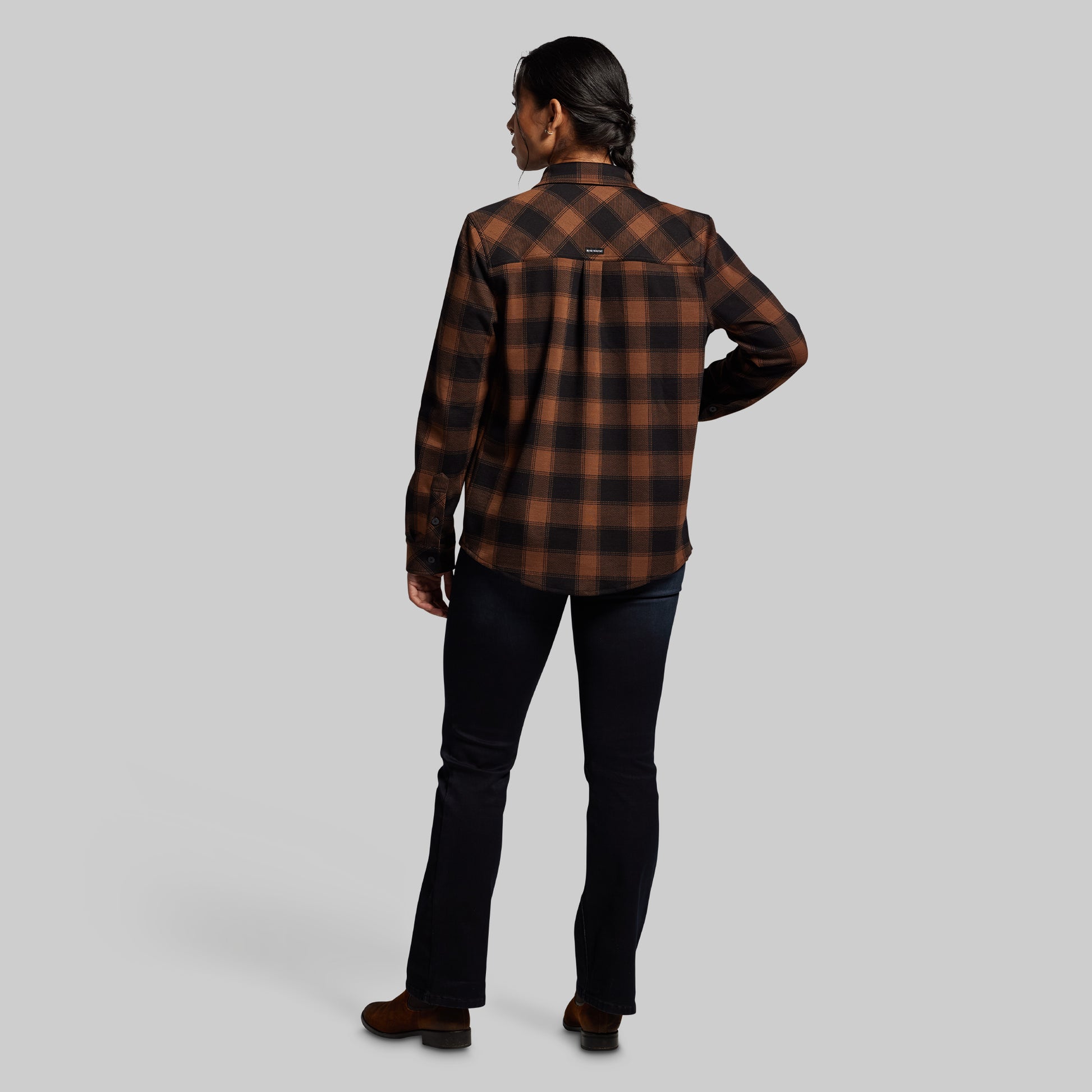 Person wearing a brown and black plaid shirt on a gray background