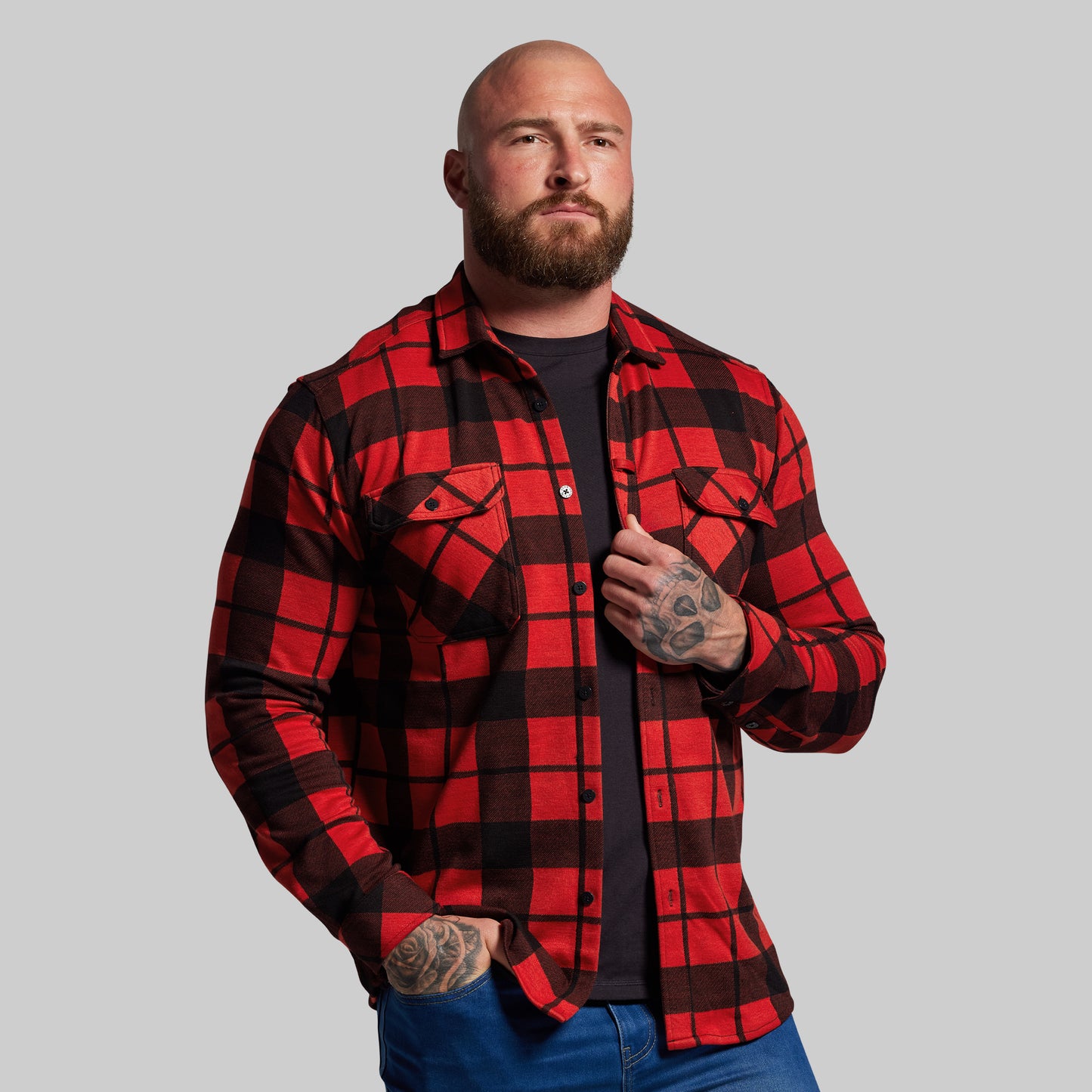 Man wearing a red and black plaid shirt against a gray background