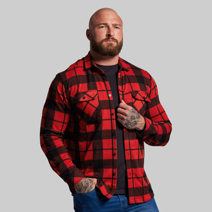 Man wearing a red and black plaid shirt against a gray background