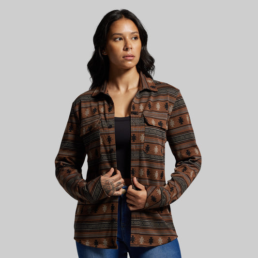 Woman wearing a patterned brown shirt against a gray background