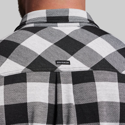 Black and white checkered shirt with 'Born Primitive' logo on a gray background