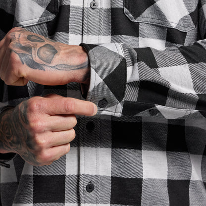 Person wearing a black and white checkered shirt adjusting sleeve cuff.