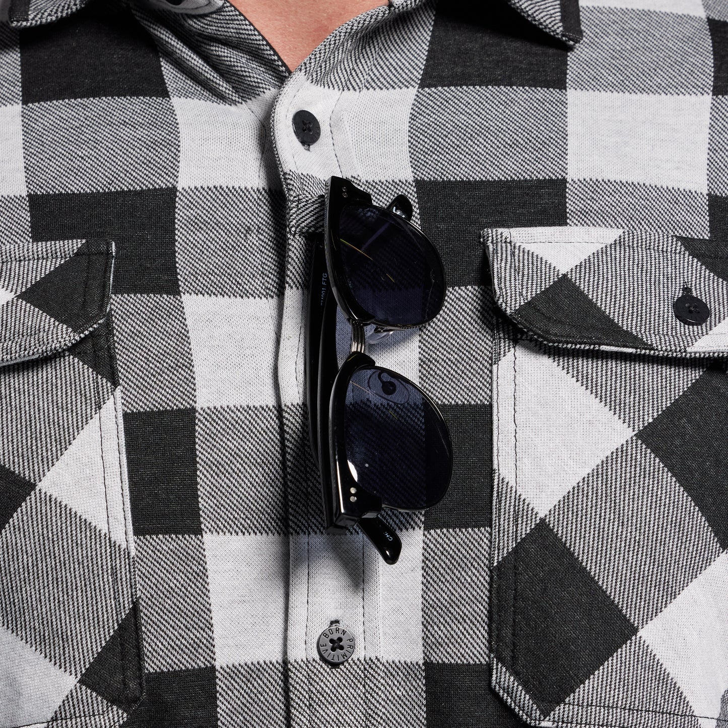 Black and white checkered shirt with sunglasses hanging from sunglass loop