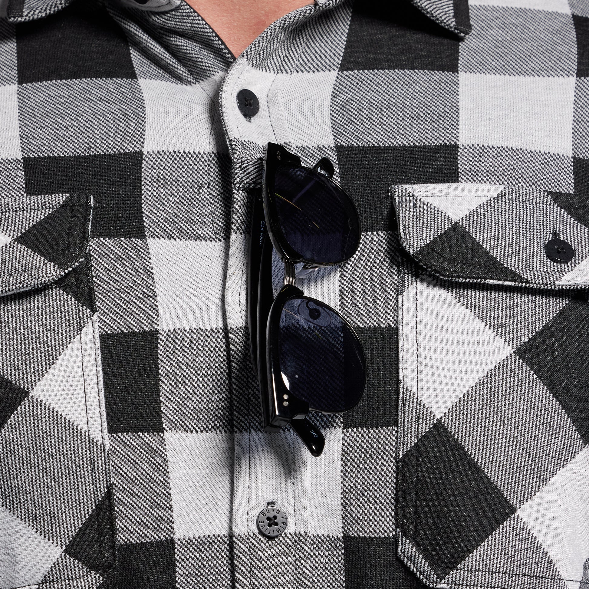 Black and white checkered shirt with sunglasses hanging from sunglass loop