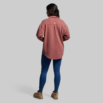 Person wearing a pink shirt and blue jeans on a gray background