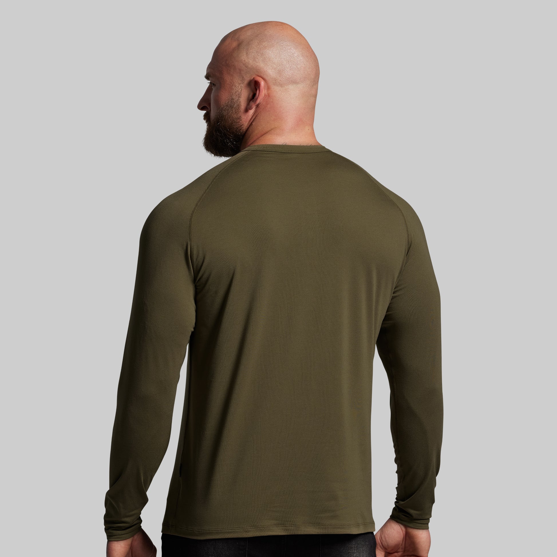 Man wearing an olive green long-sleeve shirt against a gray background