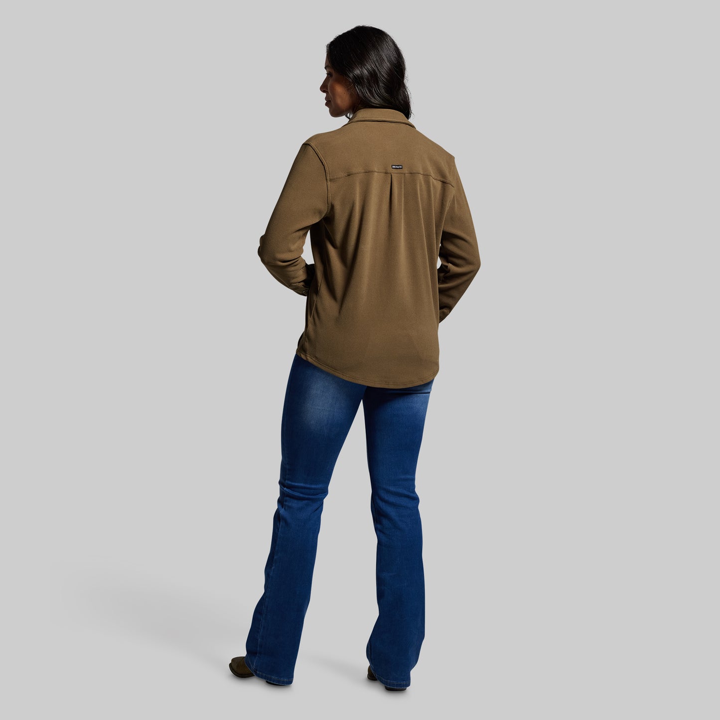 Person wearing a brown shirt and blue pants on a gray background