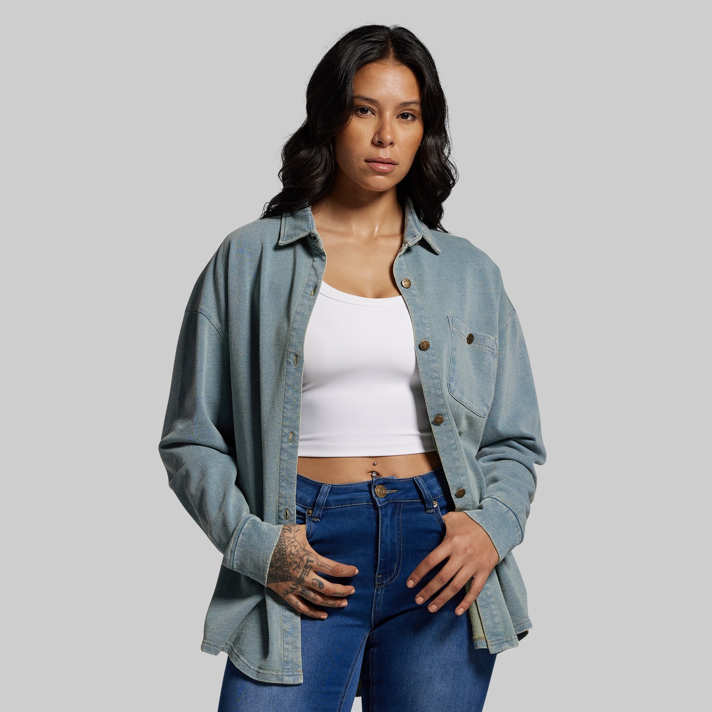 Woman wearing a denim shirt and blue jeans on a gray background