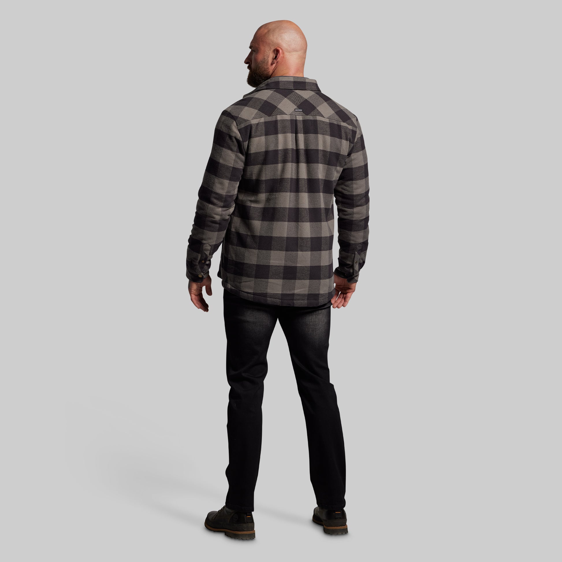 Man wearing a plaid jacket and black pants on a gray background