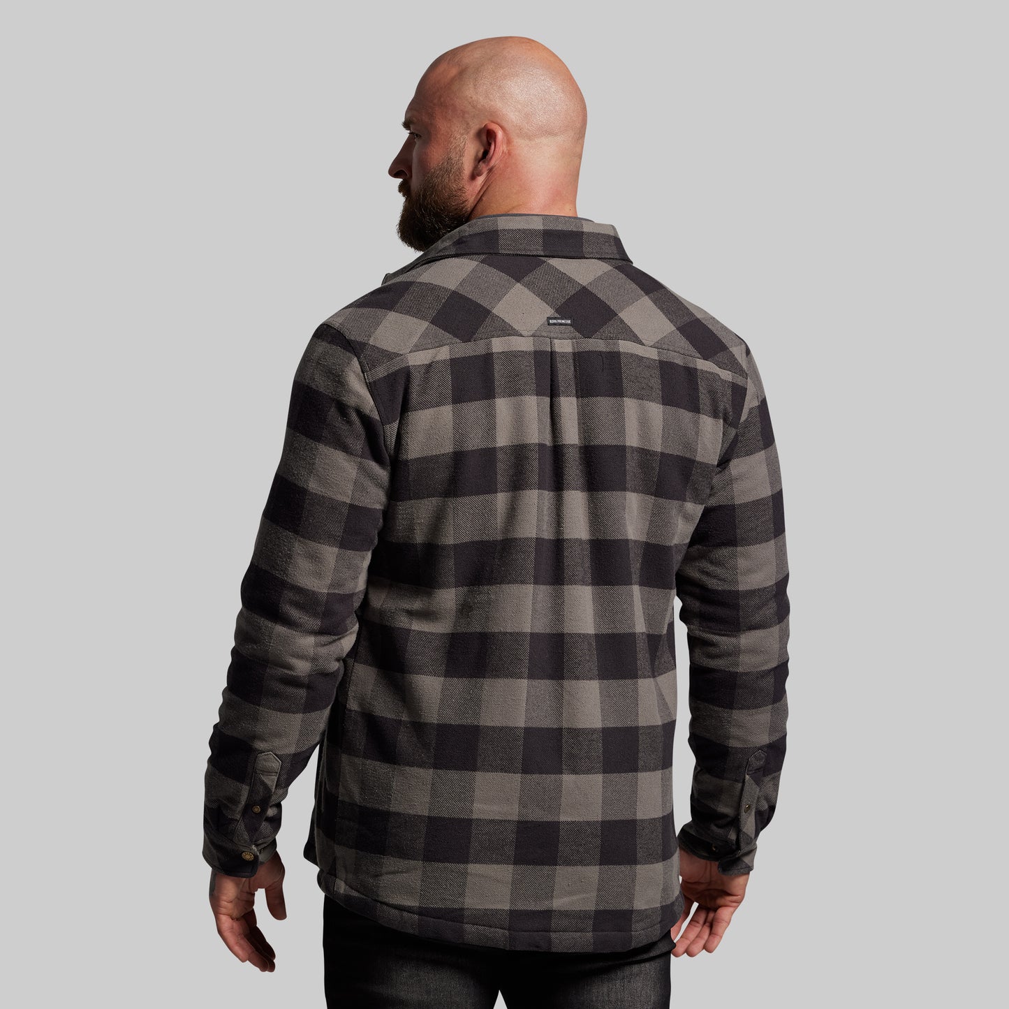 Man wearing a gray and black plaid jacket on a light gray background