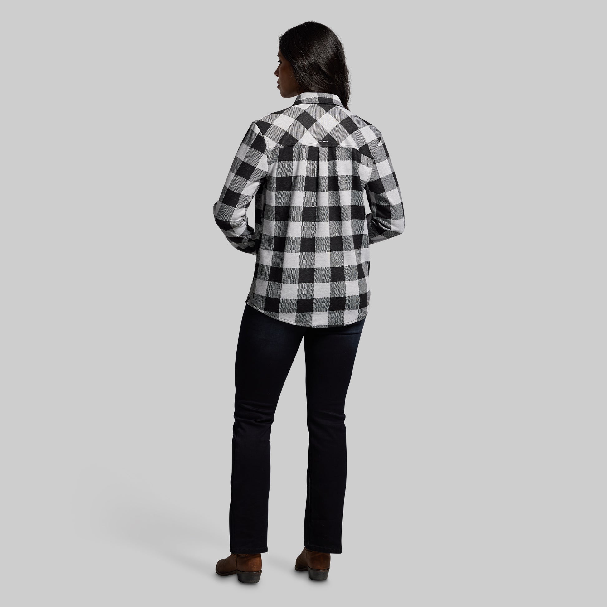 Person wearing a black and white checkered shirt on a gray background