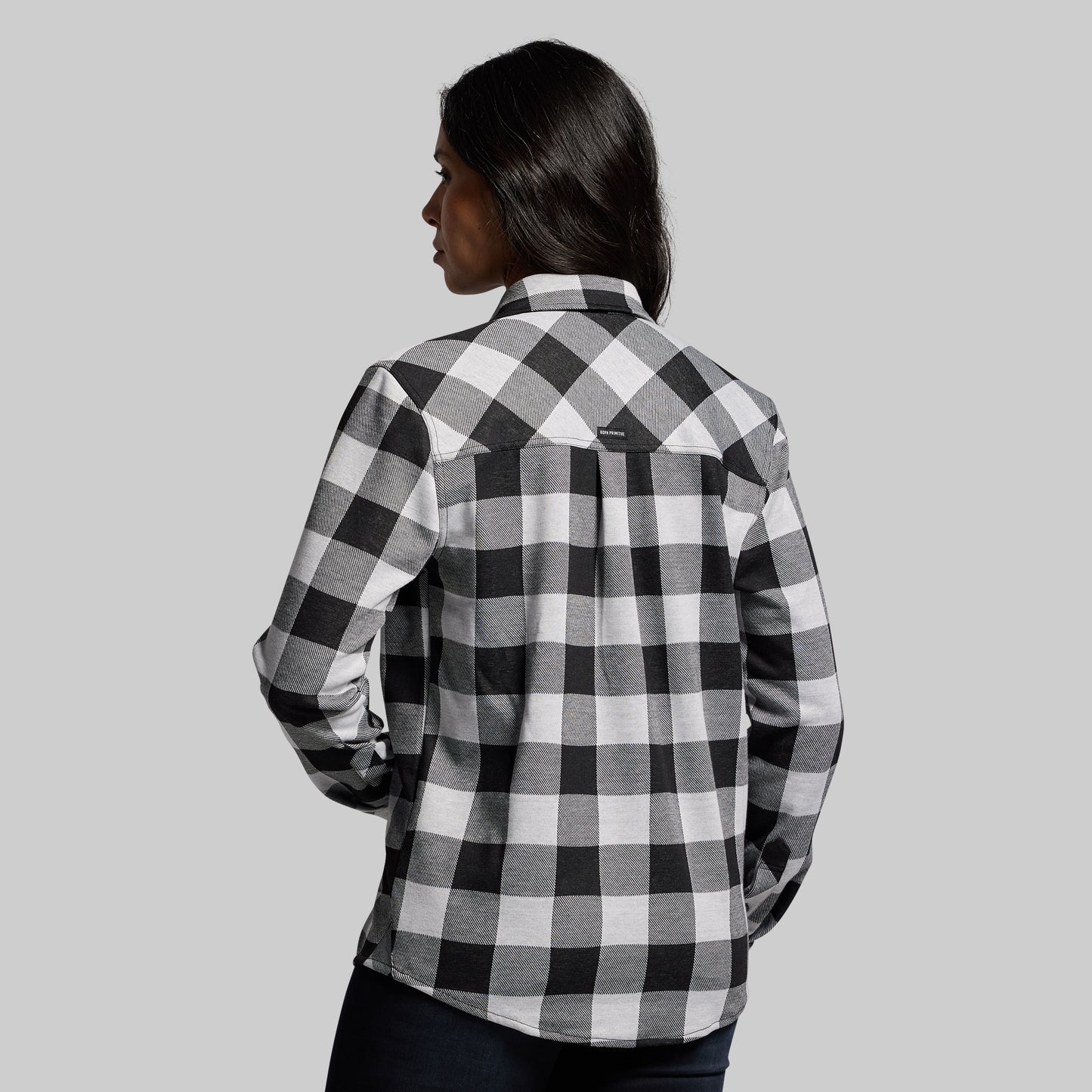 Person wearing a black and white checkered shirt against a gray background