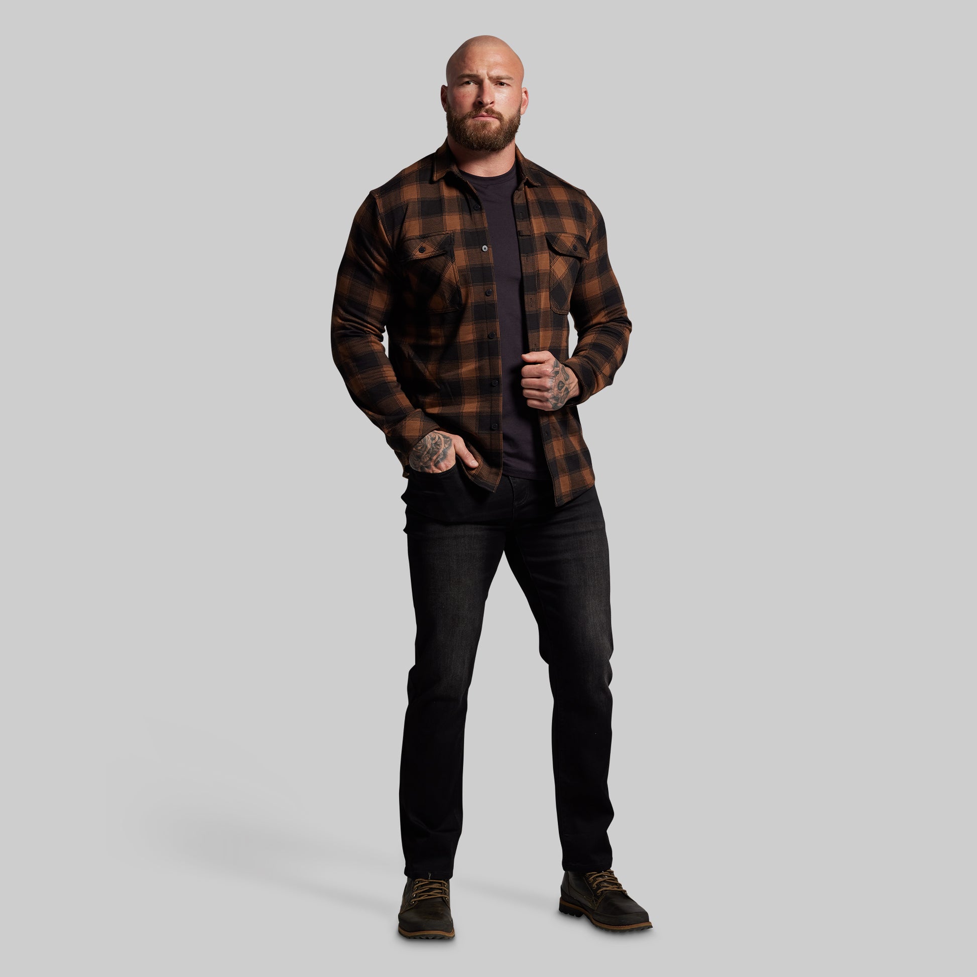 Man wearing a plaid shirt and black pants on a gray background