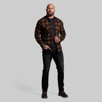 Man wearing a plaid shirt and black pants on a gray background