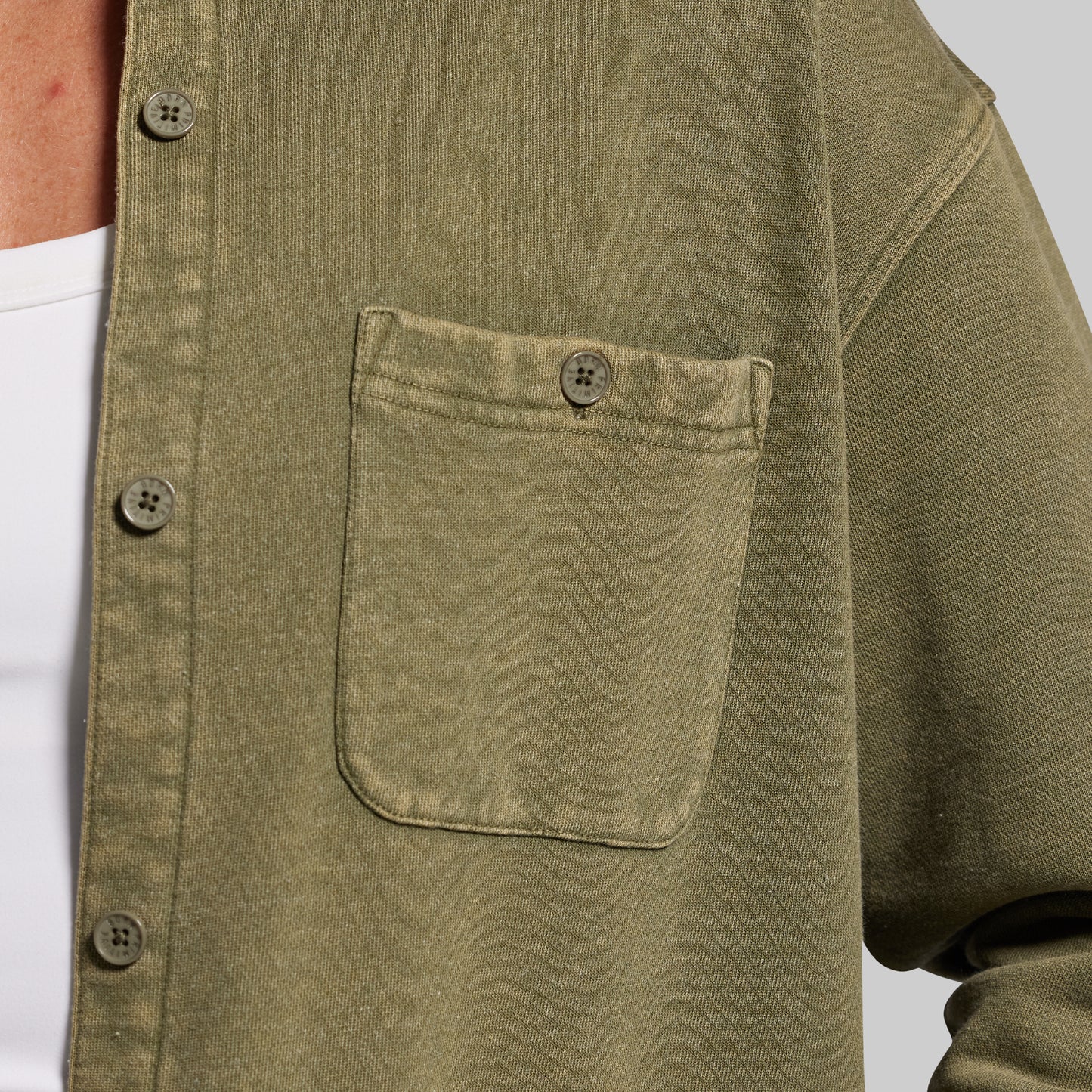 Close-up of a green shirt with a pocket and buttons on a white background