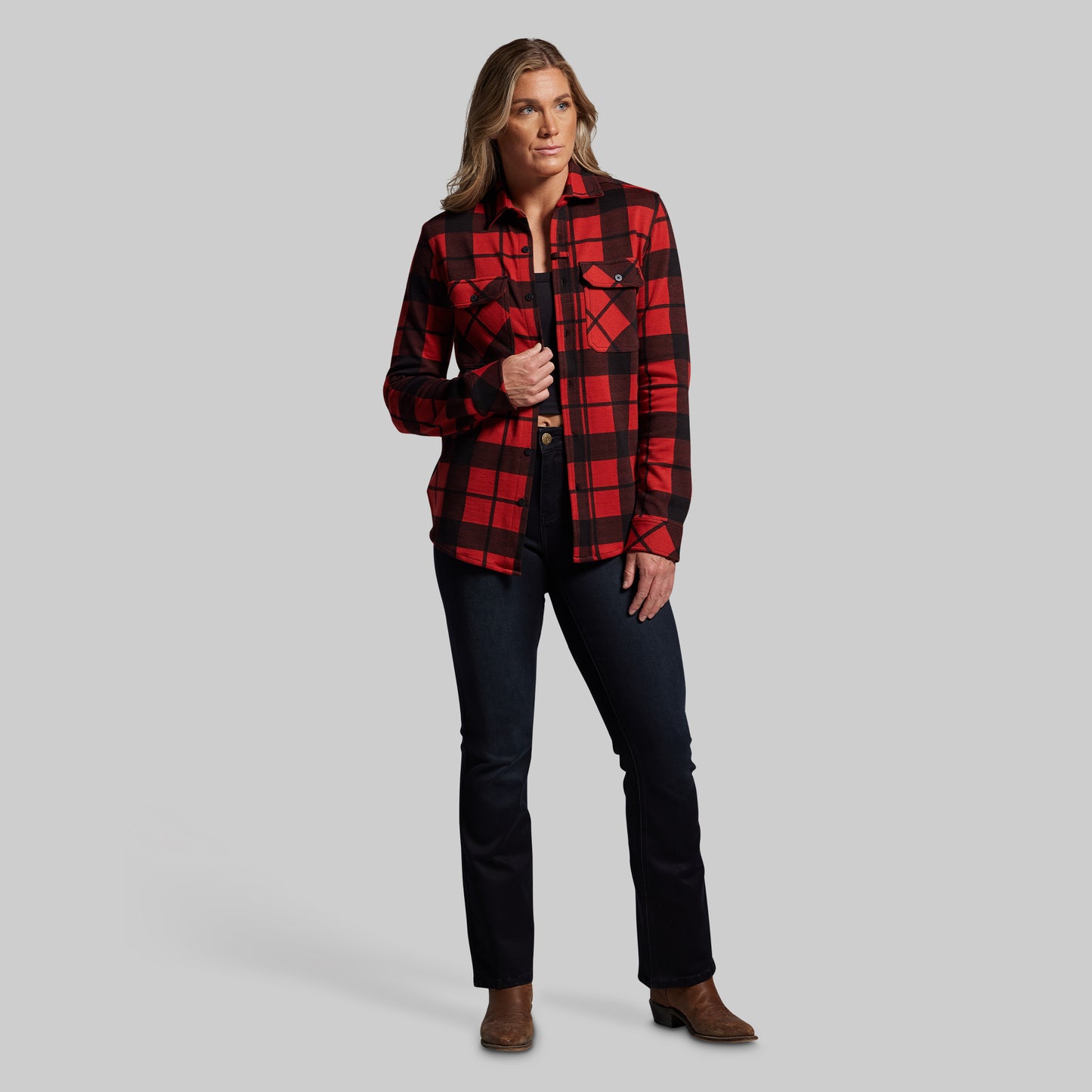 Woman wearing a red and black plaid shirt with black pants on a gray background