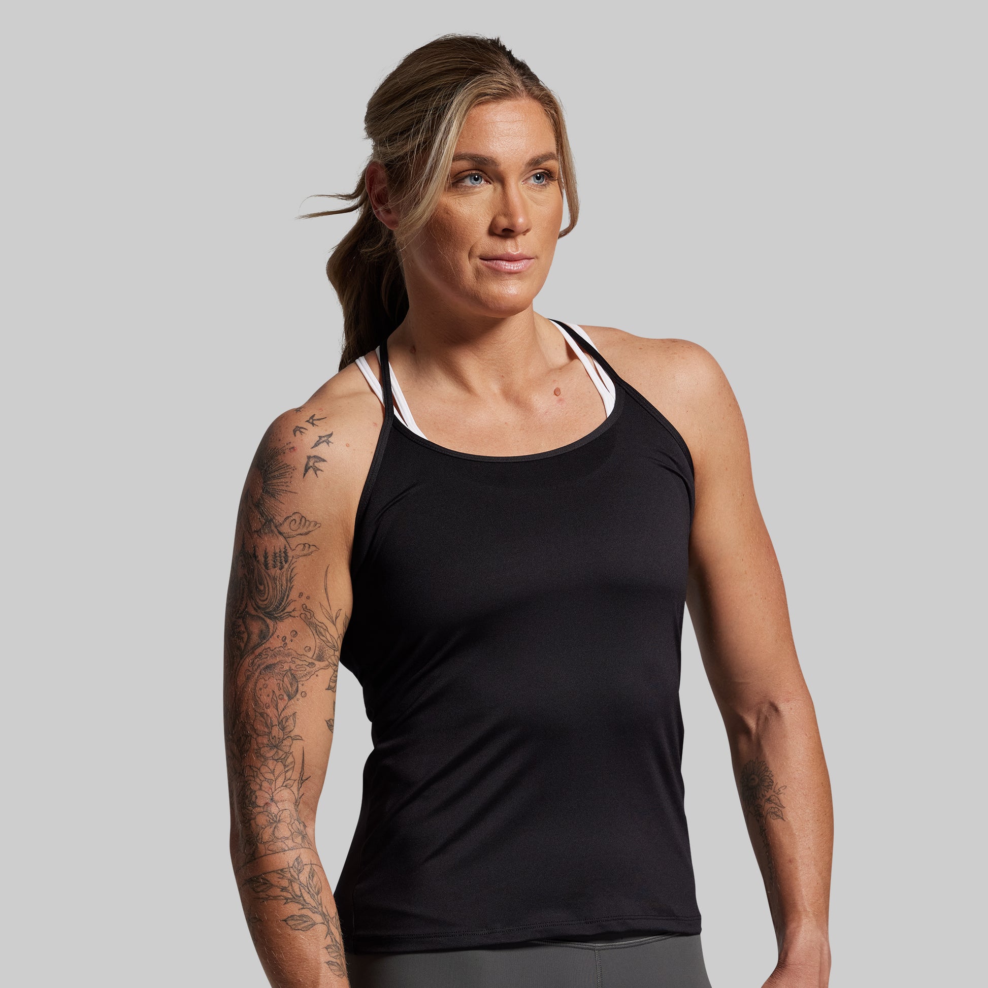 Woman wearing a black tank top against a gray background