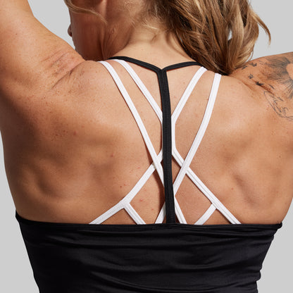 Woman wearing a black tank top with a racerback design on a gray background