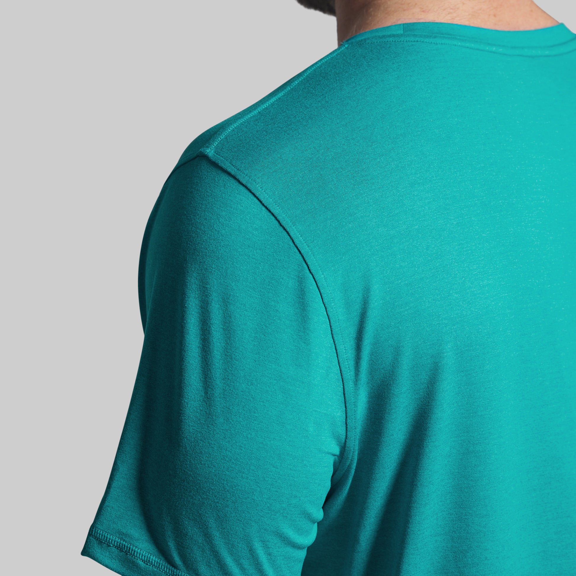 Teal athletic shirt worn by a person on a gray background