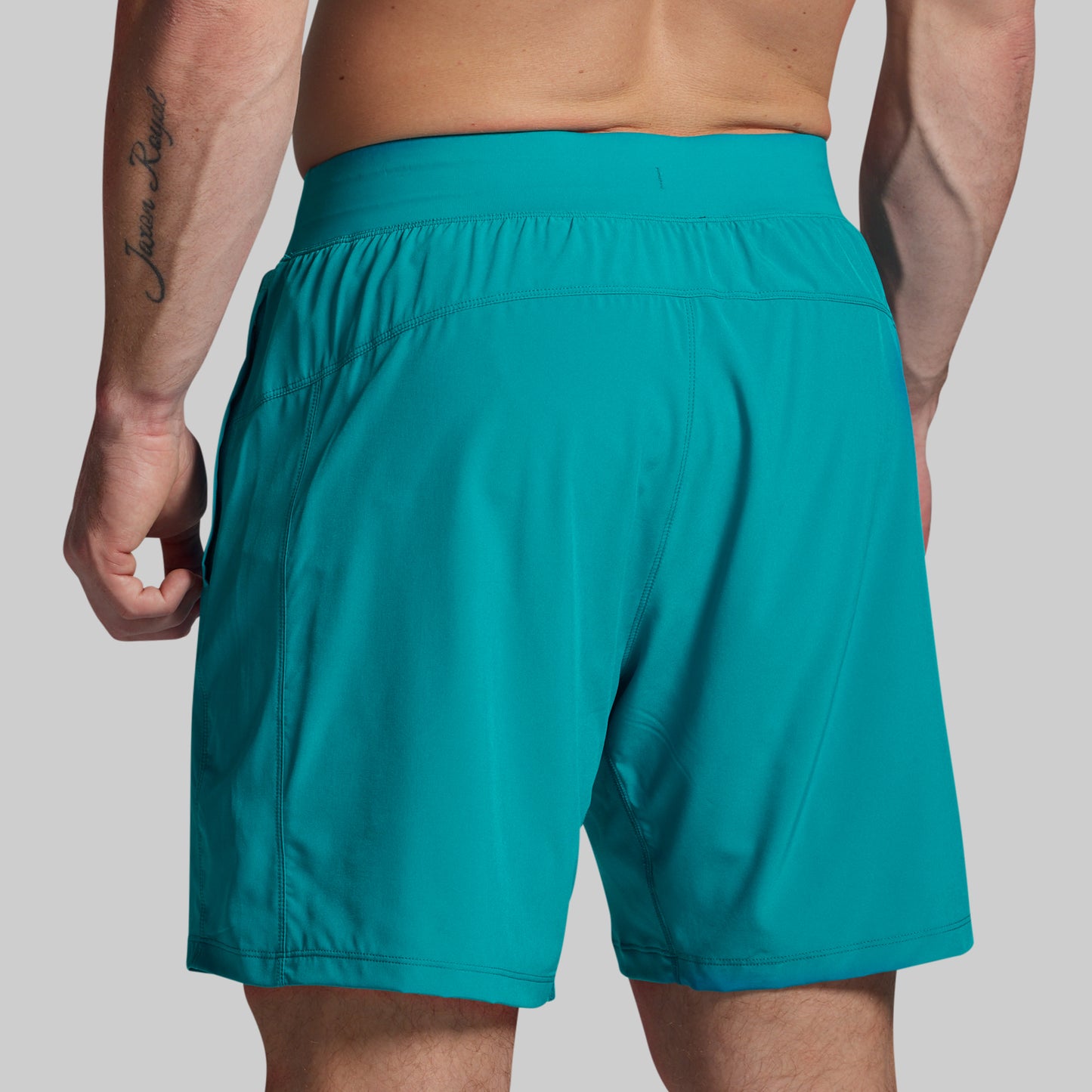 Teal shorts worn by a person on a plain background
