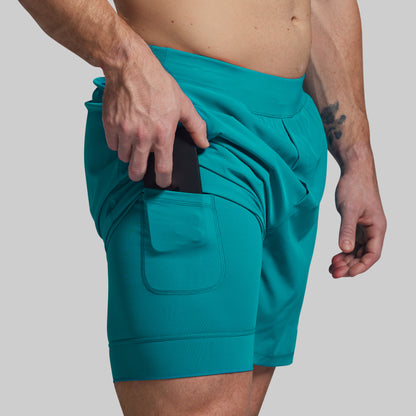 Teal shorts worn by a person on a plain background