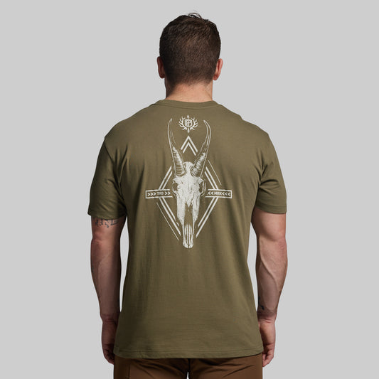 Man wearing an olive green t-shirt with a deer skull design on the back against a gray background